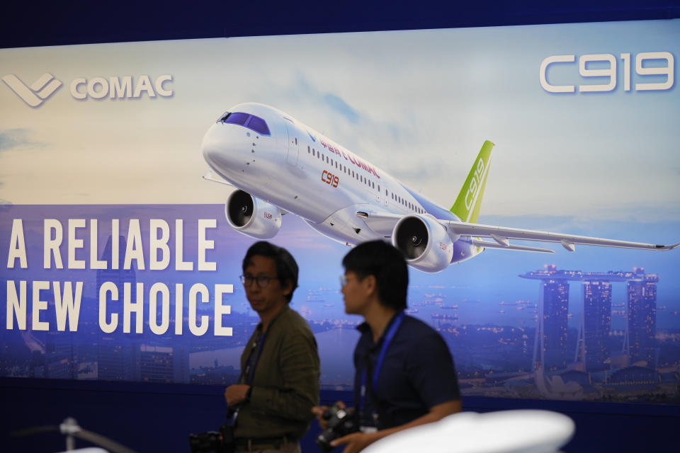 Visitors walk in front of a poster of China's Comac C919 aircraft during the first day of Singapore Airshow in Singapore, Tuesday, Feb. 20, 2024. The Singapore Airshow, Asia's largest, kicked off Tuesday with an array of aerial displays including some by China's COMAC C919 narrow-body airliner.(AP Photo/Vincent Thian)