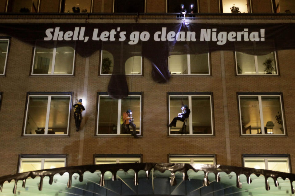 -FILE- In this Wednesday, Jan. 26, 2011, file photo Activists from Milieudefensie, the Dutch arm of the Friends of the Earth environmental organization, attach a banner and plastic made to look like dripping oil, to the Shell headquarters in The Hague, Netherlands. A landmark legal battle opens in The Hague, Tuesday Dec. 1, 2020, as climate change activists in the Netherlands go to court seeking an order for energy giant Shell to rein in its carbon emissions. (AP Photo/Peter Dejong)