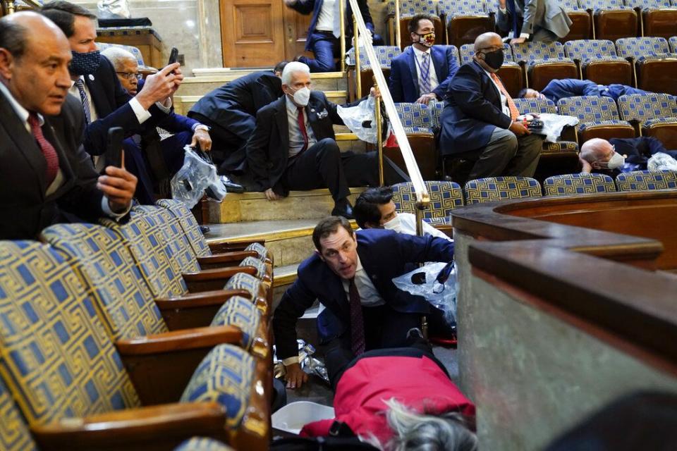 People shelter in the House gallery as protesters try to break into the House Chamber at the U.S. Capitol on Wednesday, Jan. 6, 2021, in Washington. (AP Photo/Andrew Harnik)