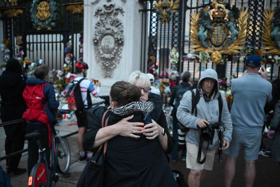 People hug each other as they gather to pay their respects outside Buckingham Palace in London on September 9, 2022, a day after Queen Elizabeth II died at the age of 96. (AFP via Getty Images)