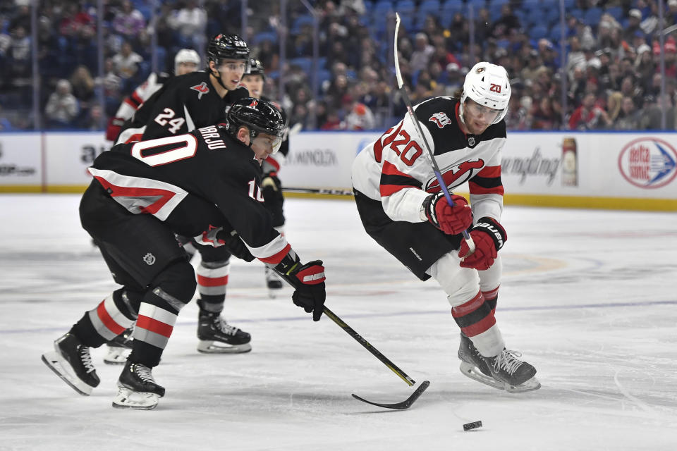 New Jersey Devils center Michael McLeod, right, moves the puck past the broken stick of Buffalo Sabres defenseman Henri Jokiharju during the first period of an NHL hockey game in Buffalo, N.Y., Friday, March 24, 2023. (AP Photo/Adrian Kraus)