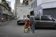 Men siphon from a car gasoline that they will store and then return to the gas station to fill up again, in the San Juan neighborhood of Caracas, Venezuela, Tuesday, Jan. 19, 2021, amid the new coronavirus pandemic. Filling stations will only fill up car and motorcycle tanks, but not containers to avoid people from storing gasoline. Venezuela's economic crisis has sent millions fleeing and those left behind lacking basic goods, including gasoline, in a country with one of the world's largest proven oil reserves. (AP Photo/Matias Delacroix)