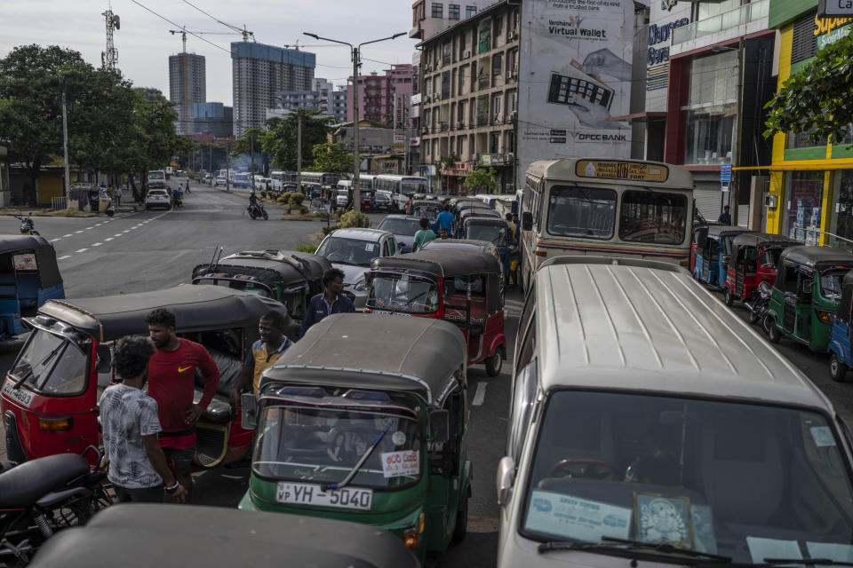 Sri Lankans wait in queue to buy petrol at a fuel station, in Colombo, Sri Lanka, July 17, 2022. Bankruptcy has forced the island nation's government to a near standstill. Parliament is expected to elect a new leader Wednesday, paving the way for a fresh government, but it is unclear if that's enough to fix a shattered economy and placate a furious nation of 22 million that has grown disillusioned with politicians of all stripes. (AP Photo/Rafiq Maqbool)