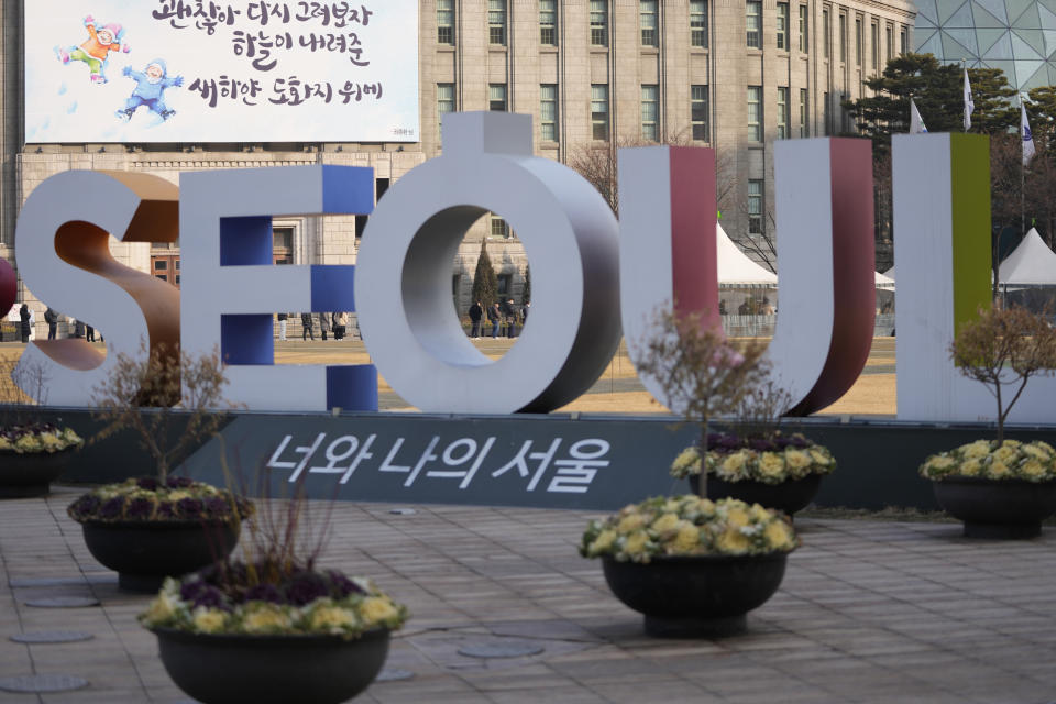 People queue in line for the coronavirus test while maintaining social distancing at a temporary screening clinic for the coronavirus near the display of the Seoul logo in Seoul, South Korea, Wednesday, Jan. 26, 2022. (AP Photo/Lee Jin-man)