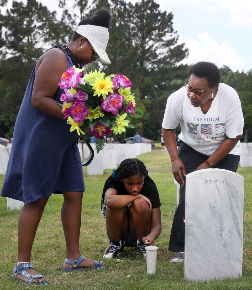 Latosha Leigh, left, visits the grave of her brother, U.S. Army Captain Toney Preston Rice with his mother Mary Rice and niece Ramya Spender, 11, as they join people gathered Monday, May 30, 2022 at the West Tennessee Veterans Cemetery in remembrance of fallen U.S. soldiers to honor Memorial Day. 