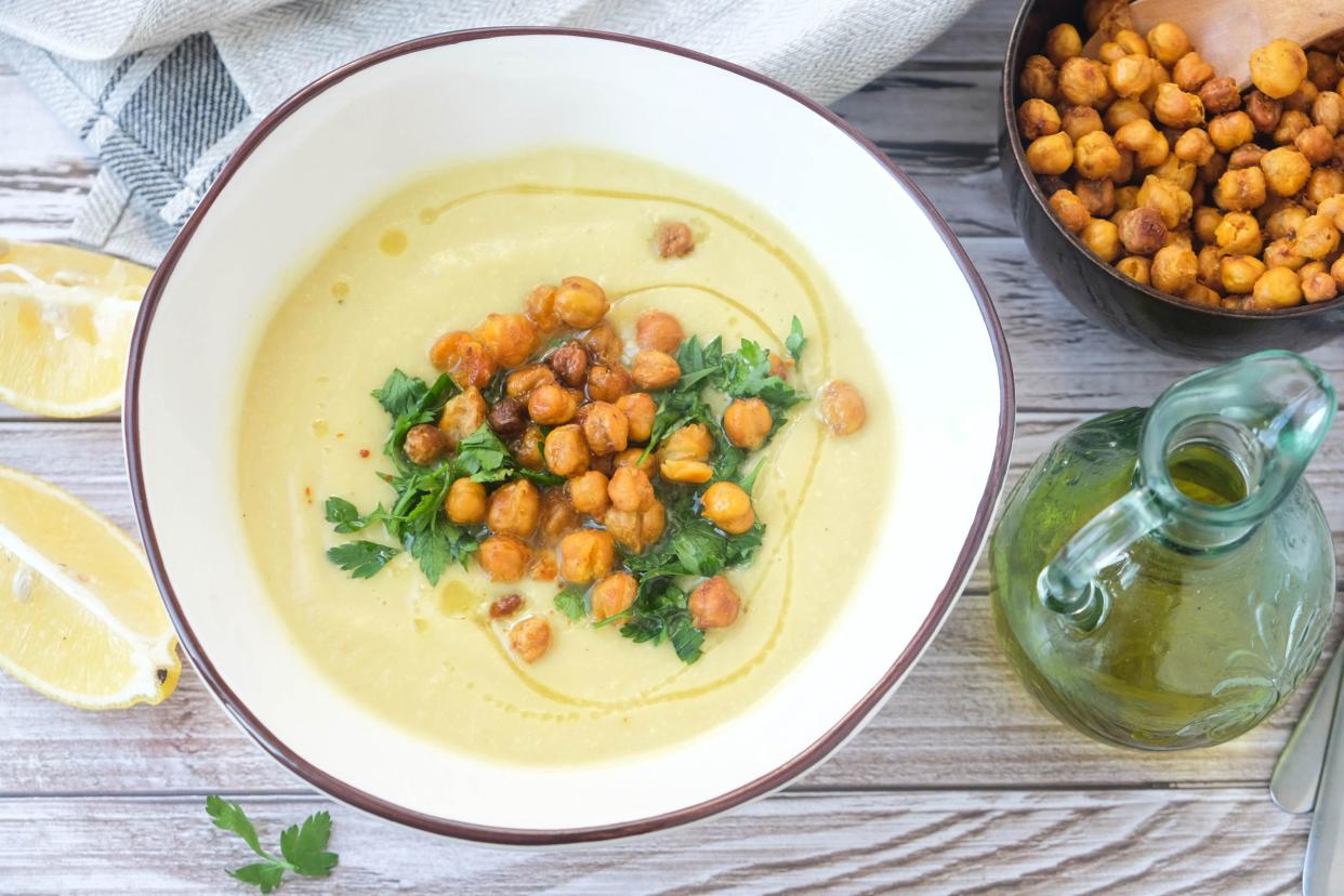 Potato and leek soup with spicy chickpeas and olive oil on the table