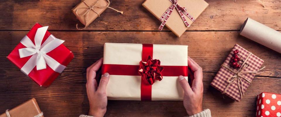 Man holding Christmas presents laid on a wooden table background