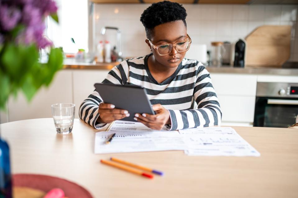 An investor studies something on paper and a tablet in a kitchen setting.