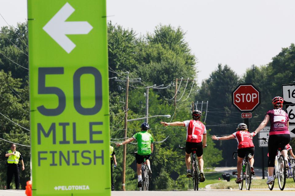 Cyclists signal their route while riding towards the intersection of Kitzmiller and Smith's Mill roads where the 50 milers and 100 mile courses split during the 6th  Pelotonia in 2014.