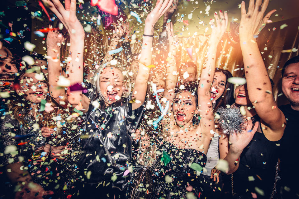 A joyous group of people celebrating with confetti flying through the air. The occasion is festive, but individual identities are not specified