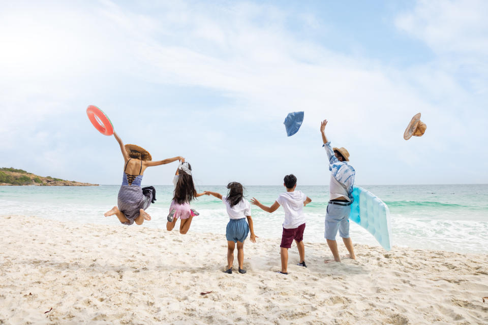Group of carefree family jumping on the beach in summer day.