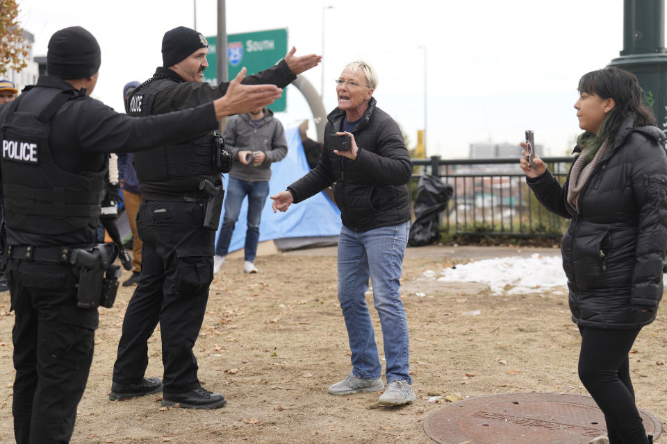 Homeless advocate Amy Beck is directed to leave by Denver Police Department officers during a city-sponsored sweep of an encampment overlooking the city skyline on Diamond Hill Wednesday, Nov. 1, 2023, in Denver. The sweep was just one of several staged in various locations across the Mile High City. (AP Photo/David Zalubowski)