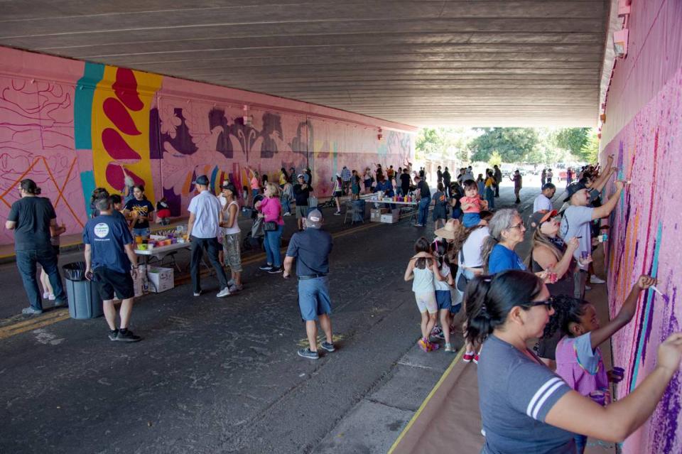 Vecinos se unen para crear un mural bajo la Highway 99 como parte del proyecto Clean California South Sac Safety & Beautification, codirigido por Jaya King y Uli Smith, durante una jornada de pintura pública en julio de 2023. Kevin Neri/Sacramento Bee file