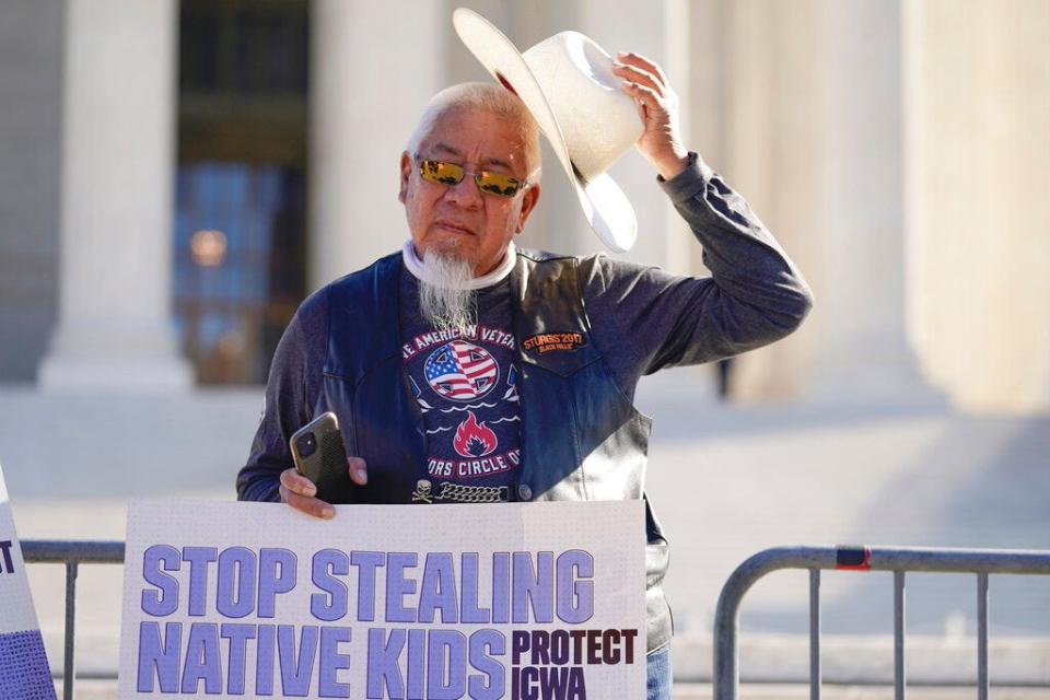 A demonstrator stands outside the U.S. Supreme Court, as the court hears arguments over the Indian Child Welfare Act on Wednesday in Washington.