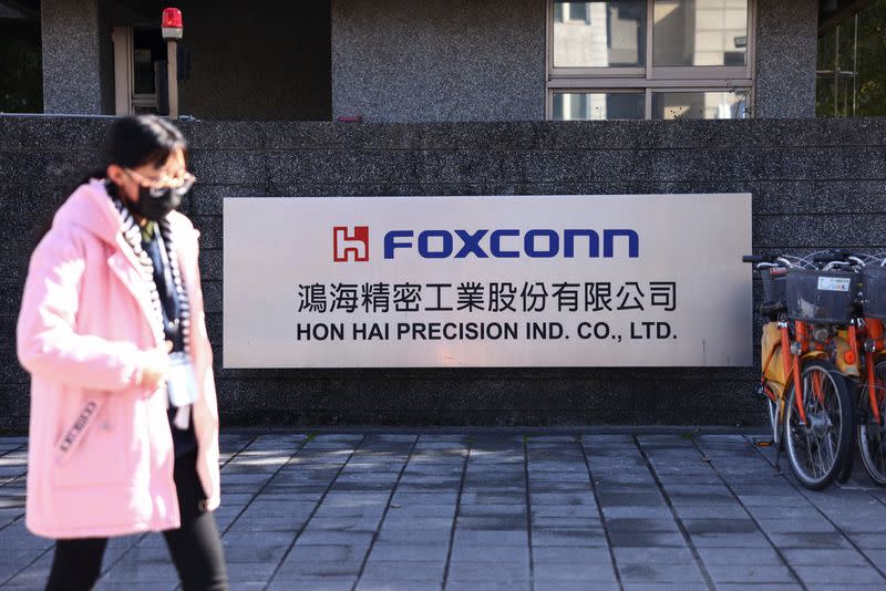 A woman walks past the logo of Foxconn outside a company's building, in New Taipe City