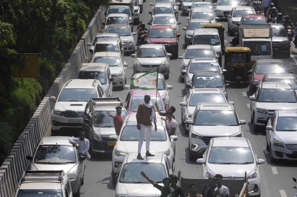 A man standing on the roof of a car as members of the Bharatiya Kisan Union (BKU) sit on protest against farm bills passed by the Parliament, blocking the Delhi-Noida border, on September 25, 2020 in Noida, India. The two bills - the Farmers (Empowerment and Protection) Agreement on Price Assurance and Farm Services Bill, 2020 and the Farming Produce Trade and Commerce (Promotion and Facilitation) Bill, 2020 - were passed by the Rajya Sabha despite uproar and strong protest by the Opposition parties in the house. (Photo by Sunil Ghosh/Hindustan Times via Getty Images)