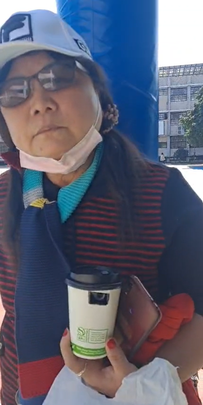 台中市第二選區補選，一名婦人持咖啡杯針孔攝影機在投票所外拍攝。（圖／林靜儀競總提供）