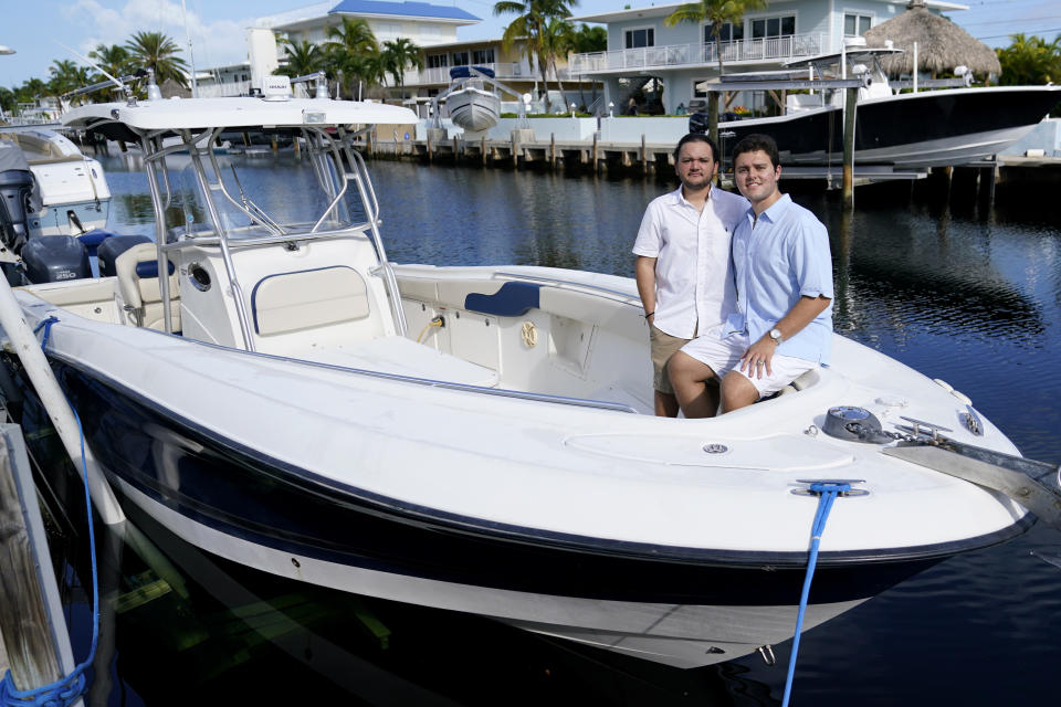 Freddy Vallejo Jr. (der) y su hermano Joel posan en una lancha anclada en la casa donde la familia pasa sus vacaciones en Cayo Largo, Florida, el 26 de septiembre del 2020. Su abuelo Jorge Vallejo, un exiliado cubano, y su tío Carlos fallecieron por el coronavirus. (AP Photo/Lynne Sladky)