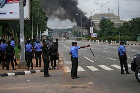 A group of police officers stand close to the site where the Shi'ite group set an ambulance and a fire engine on fire at the Federal Secretariat in Abuja