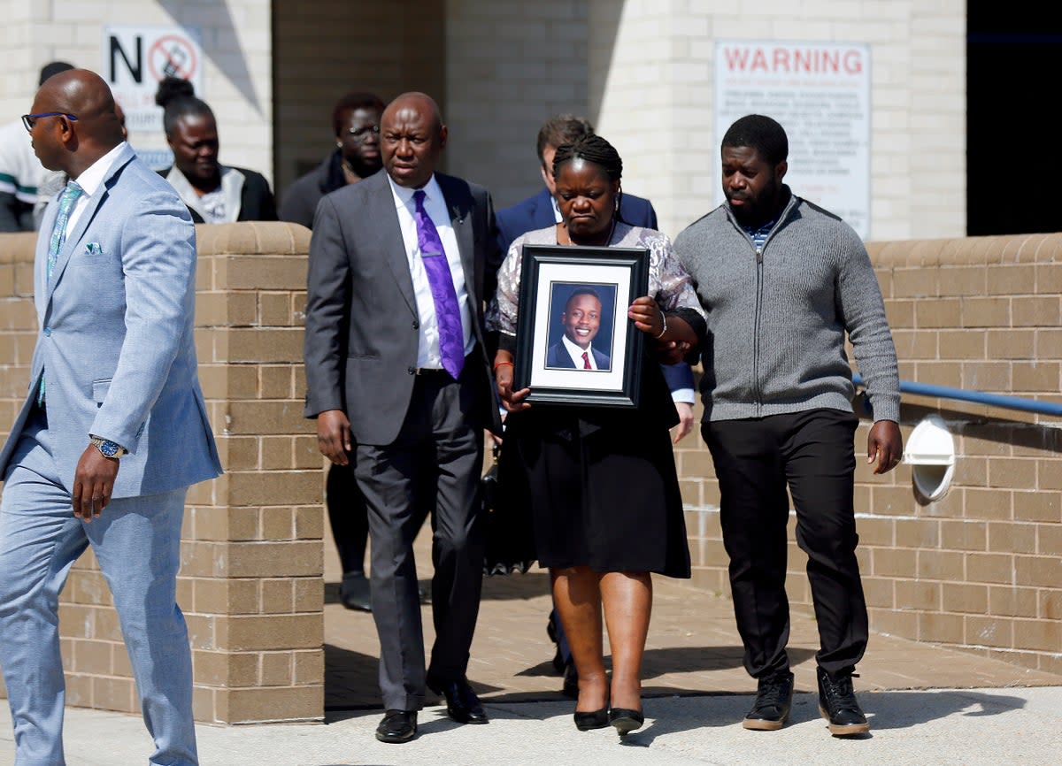 Caroline Ouko, mother of Irvo Otieno, holds a portrait of her son as she walks out of the Dinwiddie Courthouse with attorney Ben Crump (AP)