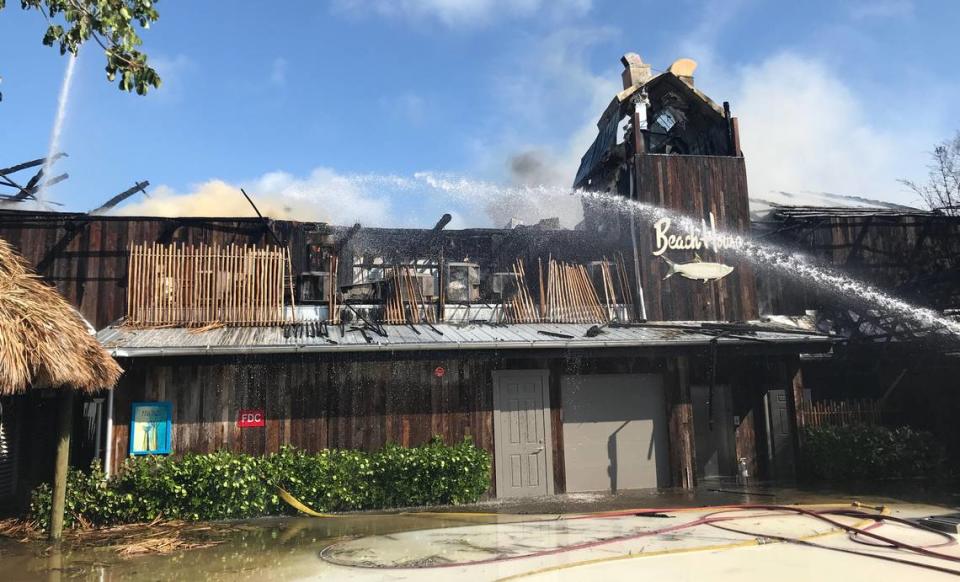 Key Largo Volunteer Fire Department firefighters spray a hose on the smoldering facade of Bungalows Key Largo, a resort that caught fire May 5, 2019. The fire was so strong that the tiki-style roof continued to smoulder almost two days after firefighters knocked down the flames.