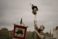 A participant in the Romula Fest historic reenactment event places a mask on a spear in the village of Resca, Romania, Saturday, Sept. 3, 2022. Members of historic NGOs and volunteers gathered in a field outside a southern Romanian village, once part of the Romula Malva, Roman Empire era city, aiming to raise awareness for history through realistic reenactments of battles between Roman legions and local Dacian tribes.(AP Photo/Andreea Alexandru)