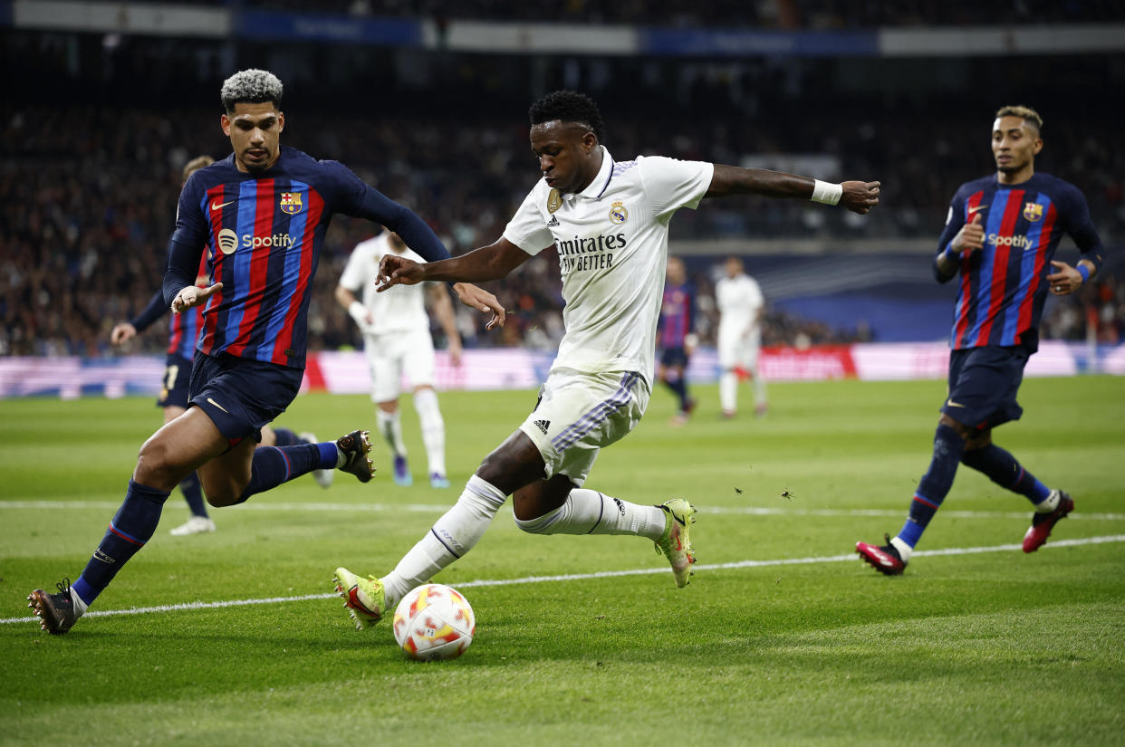 Real Madrid's Vinicius Junior (centre) in action with Barcelona's Ronald Araujo (left). 