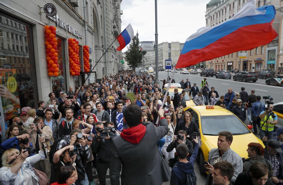 Russian opposition candidate Russian and activist Ilya Yashin, center back to a camera, waves a Russian flag during a protest in Moscow, Russia, Sunday, July 14, 2019. Opposition candidates who run for seats in the city legislature in September's elections have complained that authorities try to bar them from the race by questioning the validity of signatures of city residents they must collect in order to qualify for the race. (AP Photo/Pavel Golovkin)