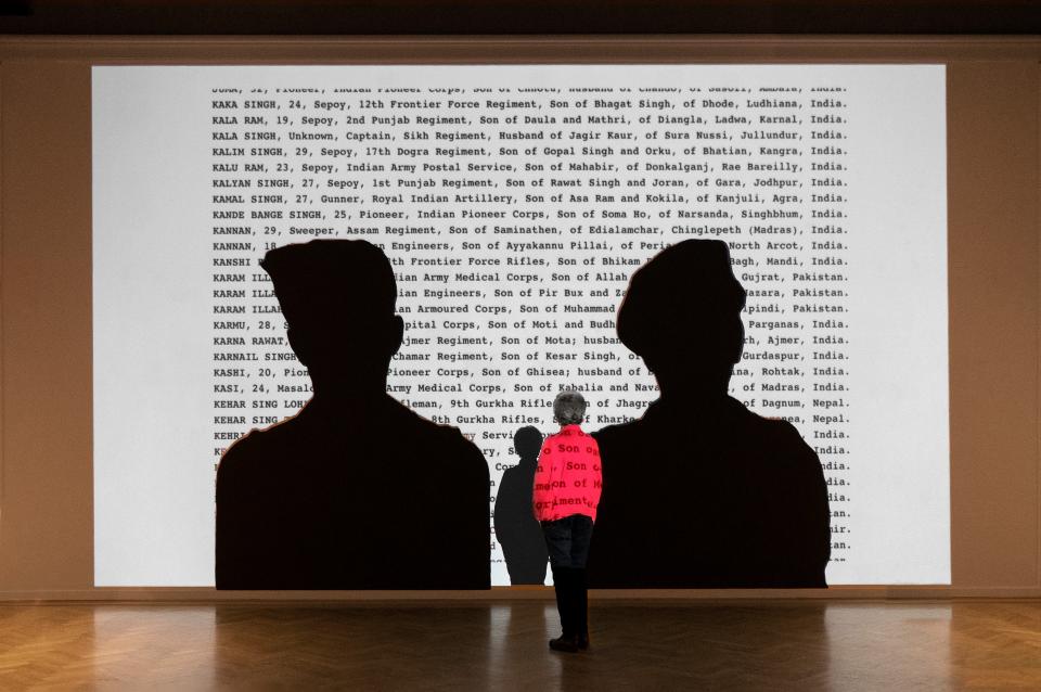 Projected onto silhouettes of two Indian soldiers are the names of some of the more than 87,000 Indian soldiers who died during World War II.