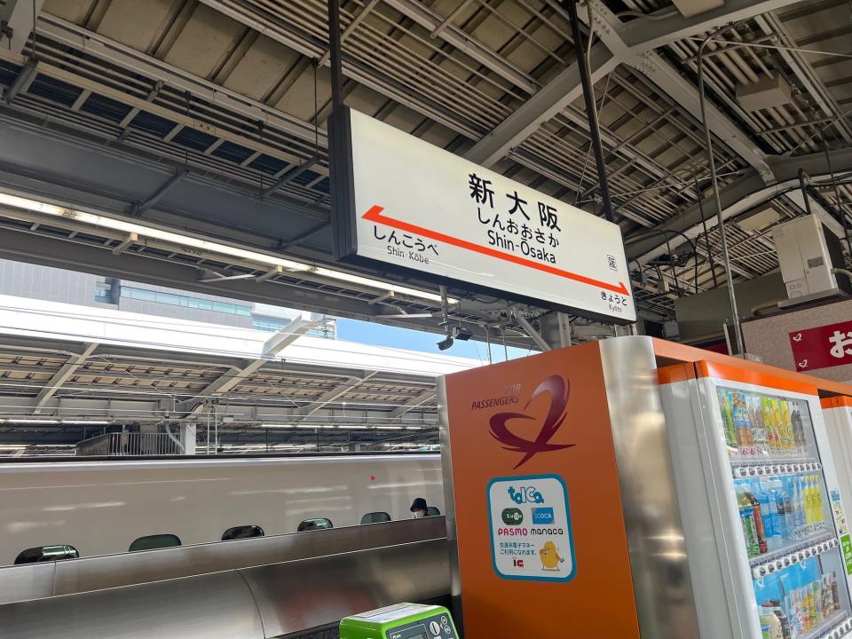 The Shin-Osaka train station sign with the N700 bullet train in the background.