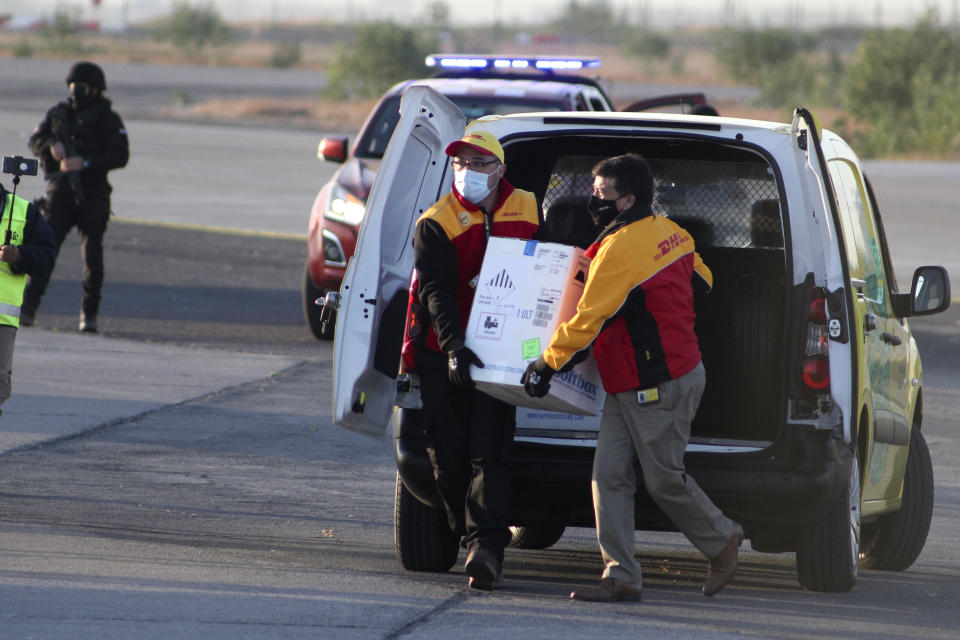 Los trabajadores llevan una caja que contiene las vacunas Pfizer COVID-19 a un helicóptero para su distribución en todo el país en el Aeropuerto Internacional Merino Benítez en Santiago, Chile, el jueves 24 de diciembre de 2020. El primer envío de la vacuna Pfizer contra COVID-19 llegó a Chile el jueves temprano desde Bélgica. (AP Foto/Esteban Felix)