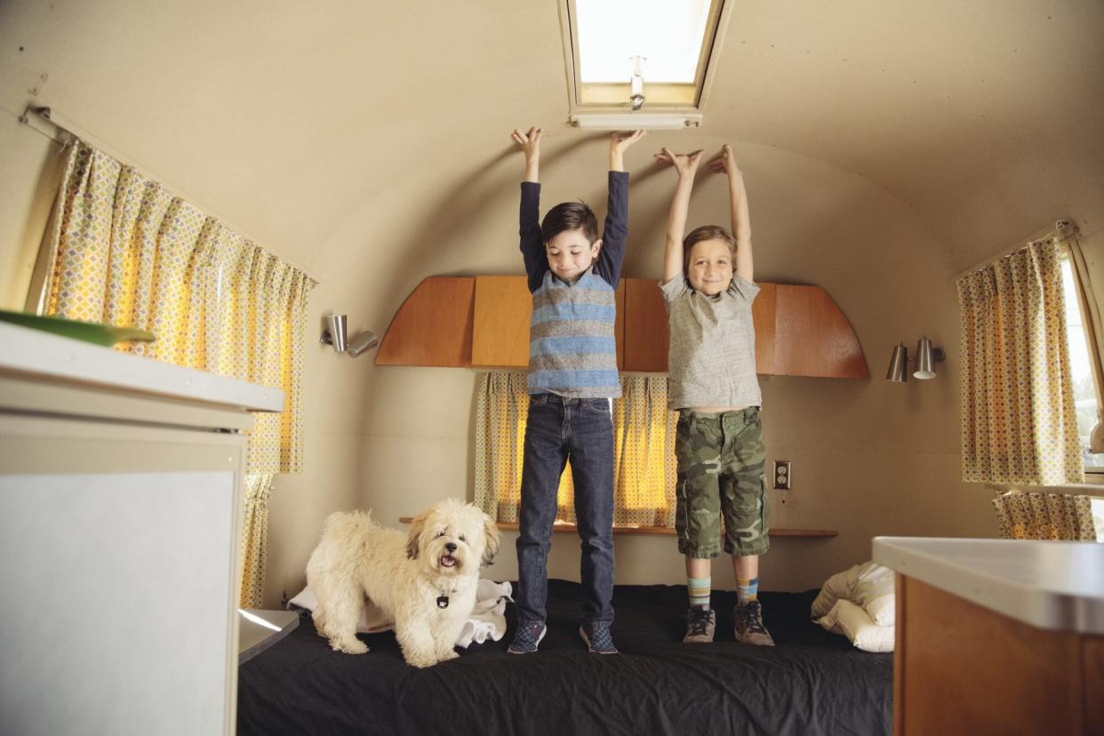 An image of boys standing on a bed in an RV.