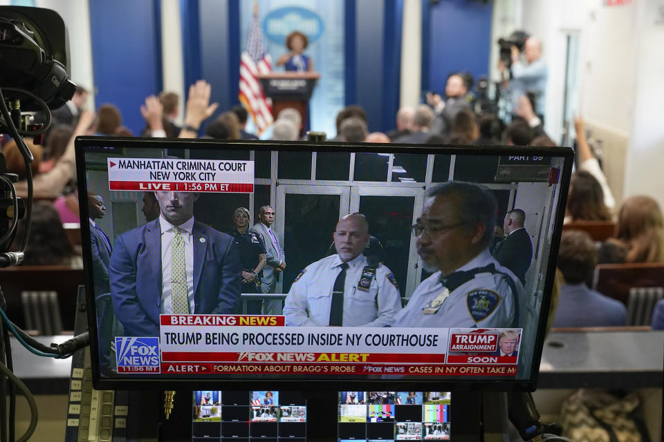 A television broadcasts news of former President Donald Trump's Manhattan courthouse appearance is seen on a video screen as White House press secretary Karine Jean-Pierre speaks during a press briefing at the White House, Tuesday, April 4, 2023, in Washington. (AP Photo/Patrick Semansky)