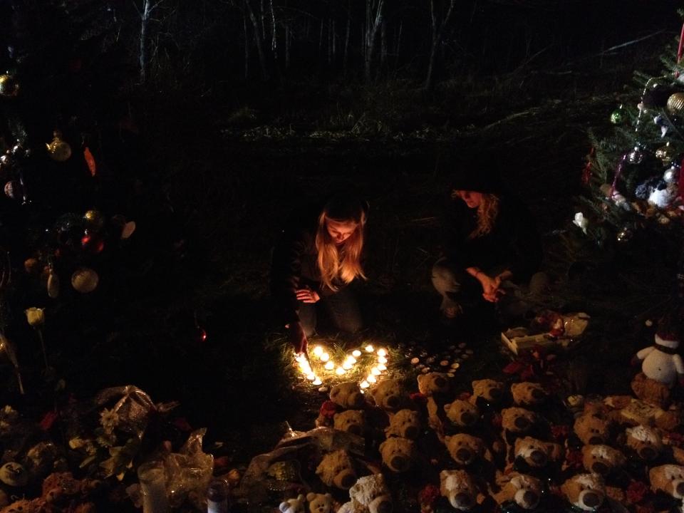 A girl lights candles displayed in the shape of a heart near the entrance to Sandy Hook Elementary School.