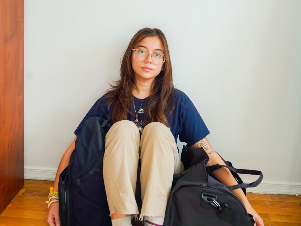 The author sits on a wood floor with two bags