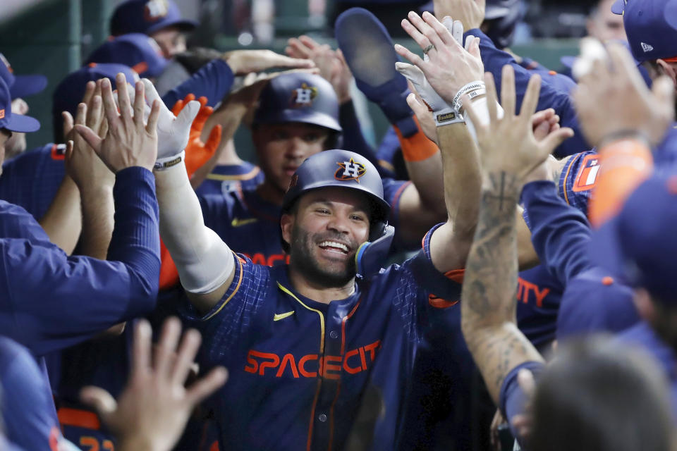 Houston Astros' Jose Altuve, center, collects high-fives in the dugout after his three-run home run against the Los Angeles Angels during the second inning of a baseball game Monday, May 20, 2024, in Houston. (AP Photo/Michael Wyke)
