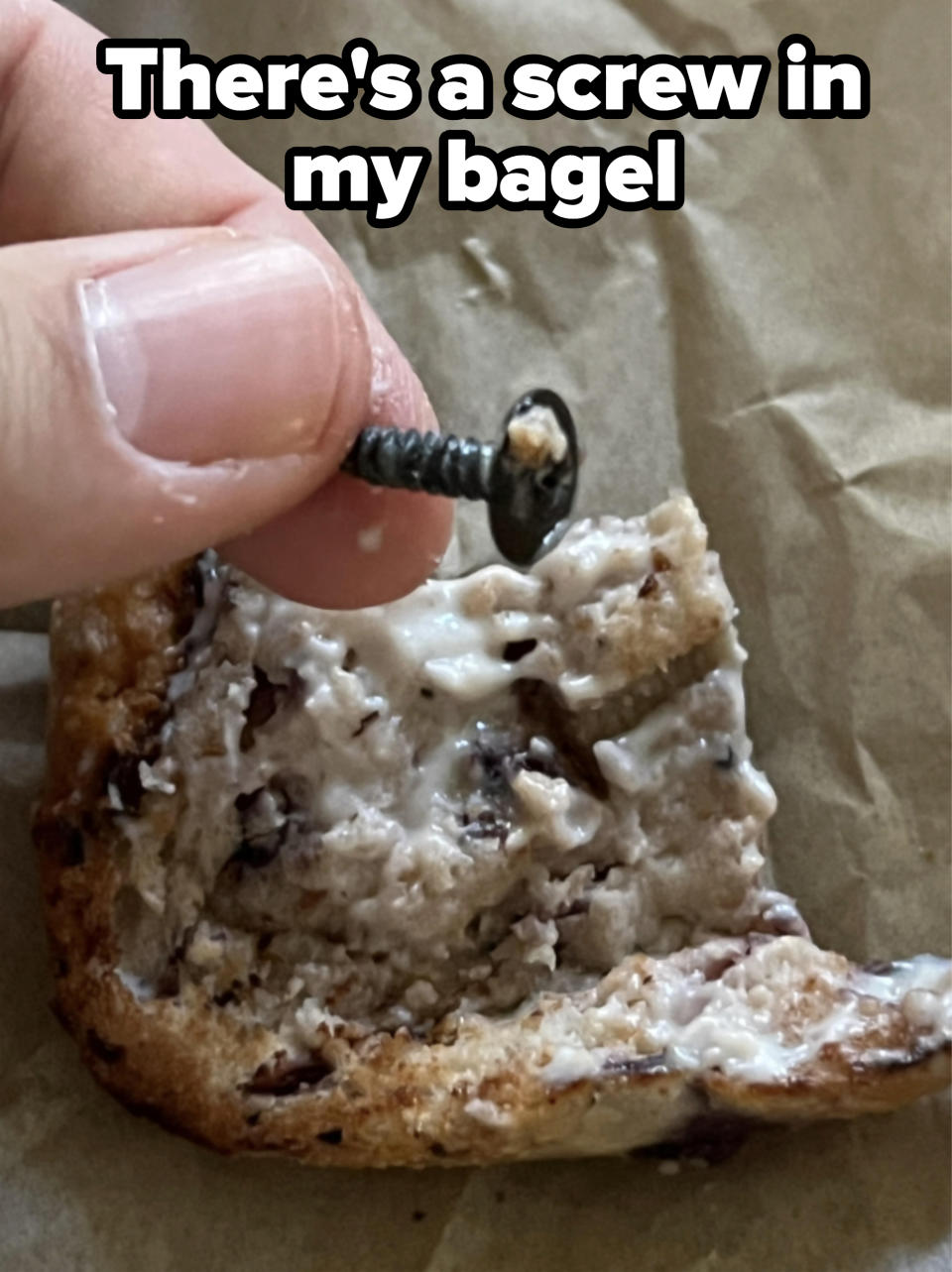 Close-up of a screw in a buttered bagel with the caption, "There's a screw in my bagel"