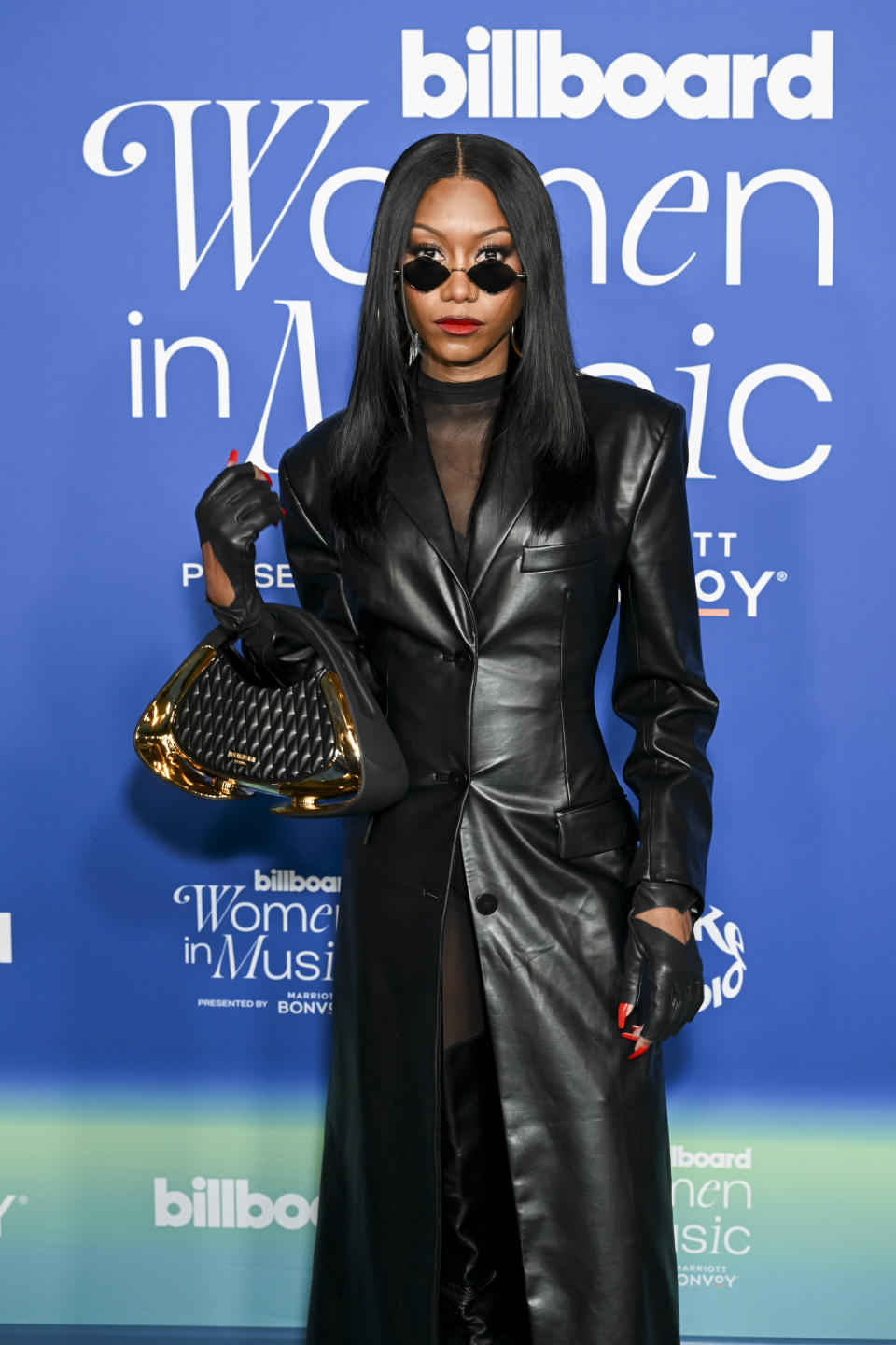 closeup of her peering over her sunglasses wearing leather gloves