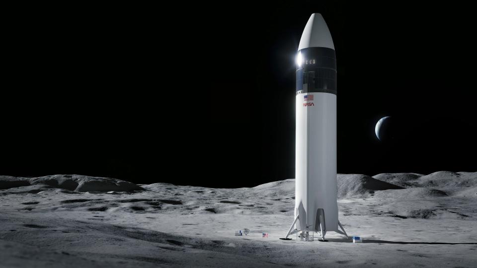 astronauts stand under a giant white rocket on the surface of the moon