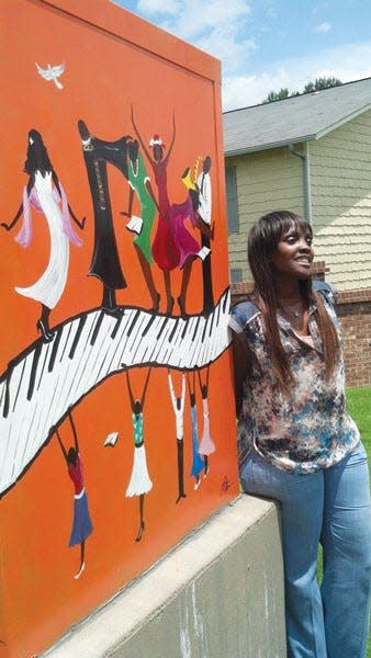 Theresa Cates with her mural on a traffic box in North Little Rock, a project by Red Door Gallery.
