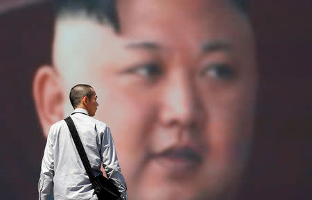 A man walks past a street monitor showing North Korea's leader Kim Jong Un in a news report about North Korea's announcement, in Tokyo, Japan, April 21, 2018. REUTERS/Toru Hanai/Files