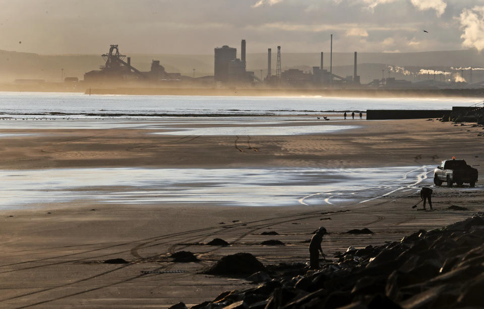 Workers on the beach in Hartlepool, England, Tuesday, Nov. 12, 2019 are backdropped by the Redcar steel plant that was shut down in 2015 and will be demolished. Political parties in Britain's Brexit-dominated December election are battling to win working-class former industrial towns, where voters could hold the key to the prime minister's office. The English port town of Hartlepool is an example. People there have long felt ignored by politicians in far-off London. (AP Photo/Frank Augstein)
