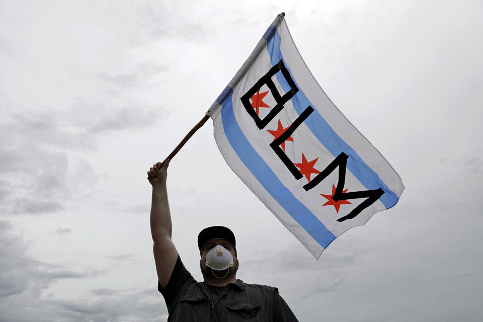 FILE - In this June 3, 2020, file photo, a protester waves a city of Chicago flag emblazoned with the acronym BLM for Black Lives Matter, outside the Batavia, Ill., City Hall during a protest over the death of George Floyd. Black Lives Matter has gone mainstream — and black activists are carefully assessing how they should respond. (AP Photo/Nam Y. Huh, File)