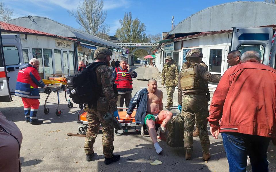 Wounded man is treated by medics at a market in the center of the Ukrainian city of Kherson following a Russian shelling - DINA PLETENCHUK/AFP
