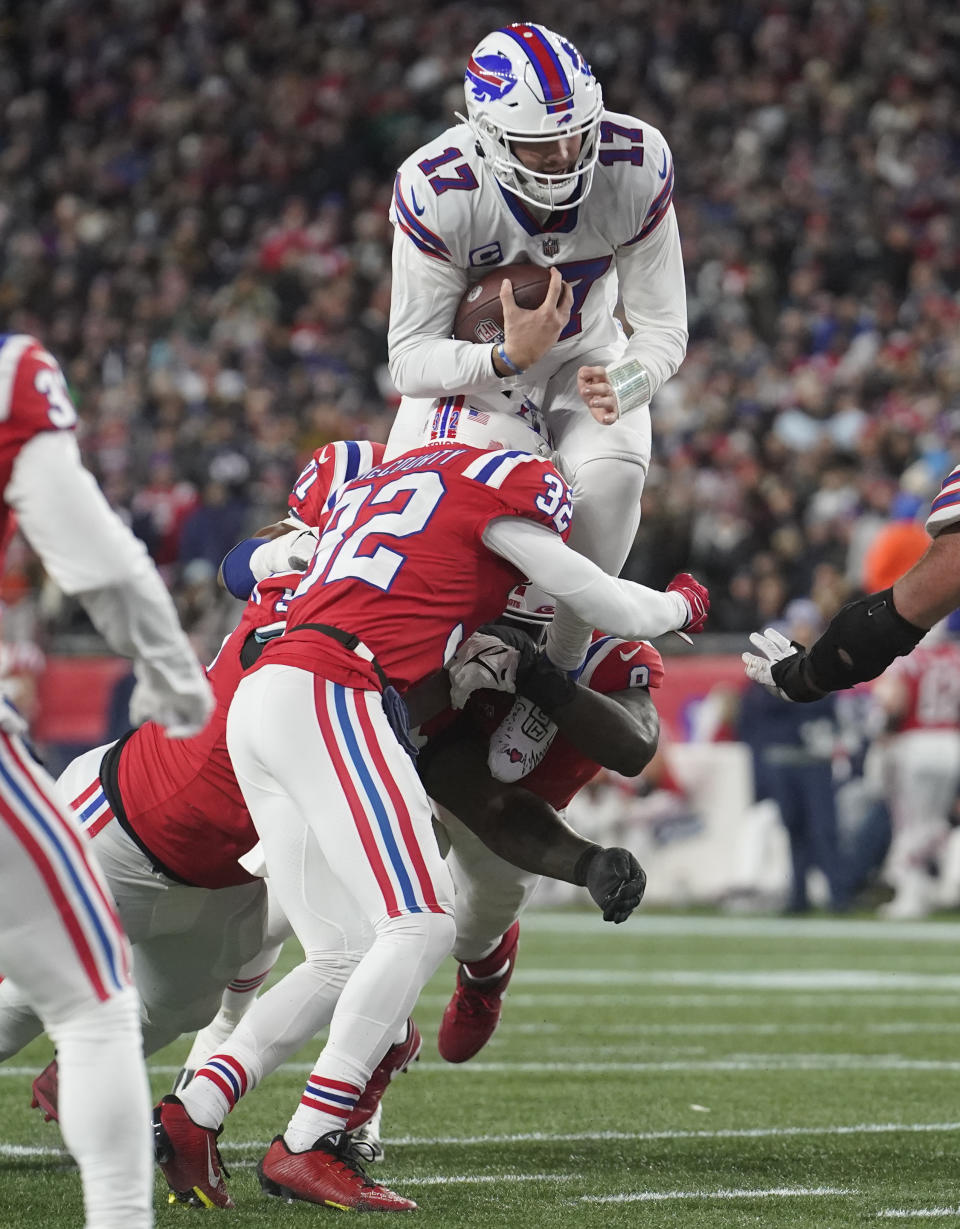 Buffalo Bills quarterback Josh Allen (17) leaps high while tackled by New England Patriots safety Devin McCourty (32) during the first half of an NFL football game, Thursday, Dec. 1, 2022, in Foxborough, Mass. (AP Photo/Steven Senne)
