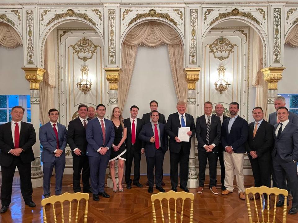 Former President Donald Trump stands with Trump Media’s Truth Social investors and supporters at Mar-a-Lago, including Patrick Orlando and Andrew Dean Litinsky to Trump’s left and Wes Moss and William Wilkerson, standing behind Donald Trump Jr., to Trump’s right.