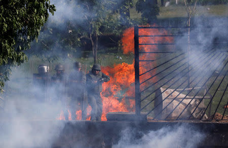 Riot security forces look through an air base fence destroyed by demonstrators rallying against Venezuela's President Nicolas Maduro in Caracas, Venezuela, May 31, 2017. REUTERS/Carlos Garcia Rawlins