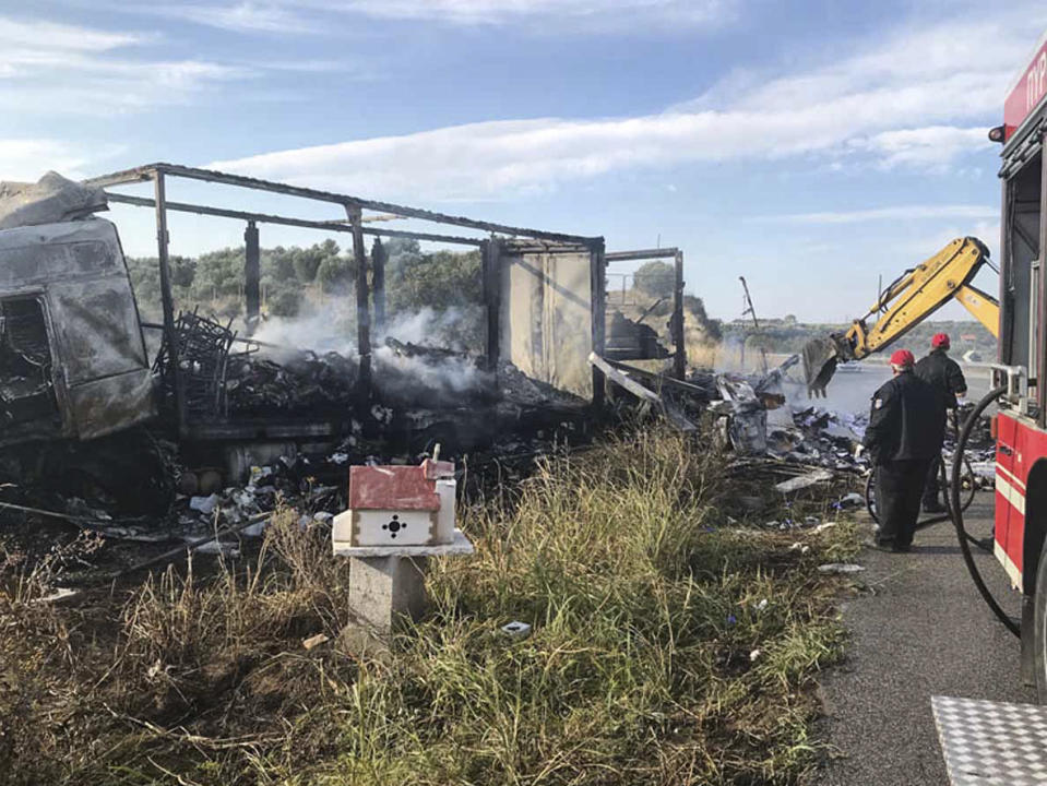 A burnt out truck on a field behind a small chapel, next to a motorway, following a collision near Greece's northern town of Kavala, Saturday, Oct. 13, 2018. A car carrying migrants collided with a truck in northern Greece on Saturday, killing 11 people, police said. (Proininews.gr via AP)