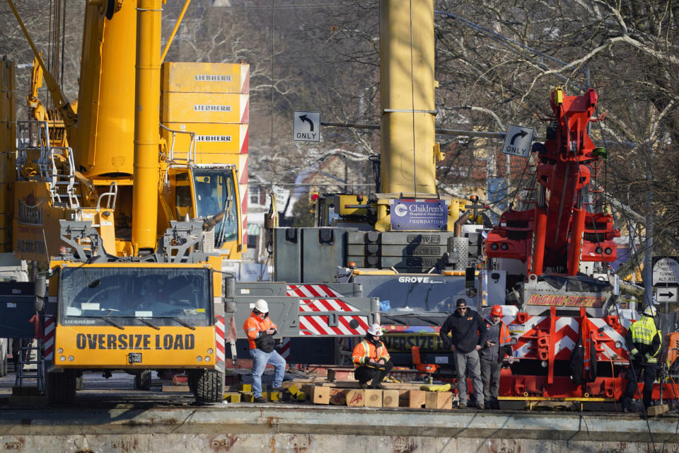Workers stand by the cranes that are being used to remove the bus that was on a bridge when it collapsed Friday as they work to remove it during the recovery process on Monday Jan. 31, 2022 in Pittsburgh's East End. (AP Photo/Gene J. Puskar)