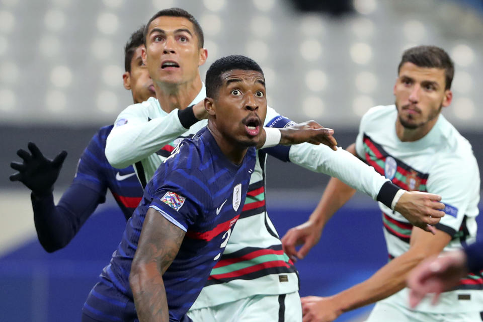 FILE - In this Sunday, Oct. 11, 2020 file photo Portugal's Cristiano Ronaldo, left, and France's Presnel Kimpembe, centre, eye the ball, during the UEFA Nations League soccer match between France and Portugal at the Stade de France in Saint-Denis, north of Paris, France. The Portuguese soccer federation says Cristiano Ronaldo has tested positive for the coronavirus. The federation says Ronaldo is doing well and has no symptoms. He has been dropped from the country's Nations League match against Sweden on Wednesday, Oct. 14. (AP Photo/Thibault Camus, File)